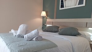 A neatly made bed with white linens, a grey throw blanket, and rolled towels. - Hotel San Martino (Lena)