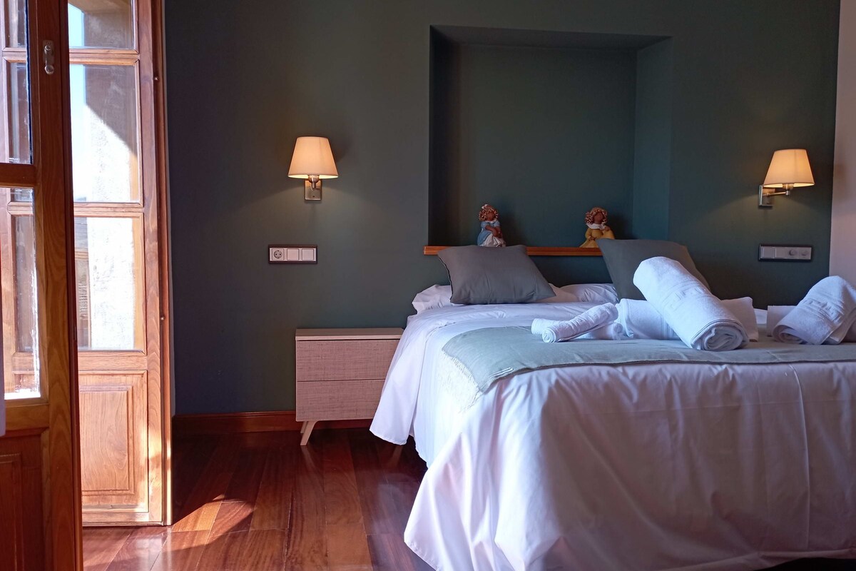 A hotel room with a bed, bedside lamps, a nightstand, a dresser, and a mirror.
