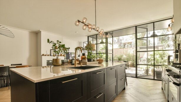 Una cocina moderna con una isla grande, muebles negros y un ventanal que ofrece vistas al exterior.