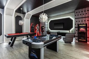 Relax in a futuristic room with a pool table, flat-screen TV, and arcade machine.