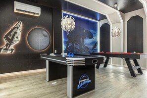 Enjoy a game of pool in our gaming area, featuring a space-themed mural and starry ceiling.
