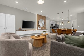 Relax in a spacious living room with a large flat-screen TV, dining area, and comfortable seating.