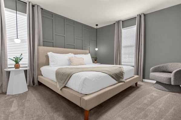 Relax in this serene bedroom with a large bed, side table, and comfortable armchair.
