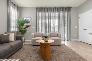 Relax in this stylish living room with a sofa, coffee table, and potted plant, surrounded by artwork and a comfortable rug.