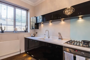 Kitchen features a gas stove, stainless steel sink, and a window with blinds.