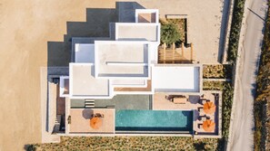 Luchtbeeld van een modern resort met meerdere gebouwen, een zwembad en buitenzitgedeeltes.