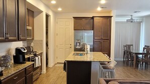 Une cuisine moderne avec des meubles en bois, un îlot central et un coin repas agrémenté d’un canapé marron.