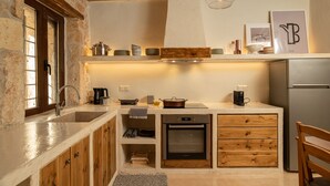 Une cuisine compacte dotée d’un four encastré, de meubles de rangement en bois, d’un évier et d’un luminaire suspendu.
