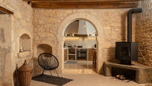 Un intérieur rustique avec des murs en pierre, une cheminée, un panier en osier et un fauteuil moderne.
