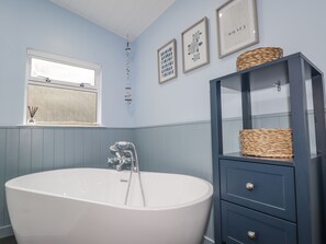 Ein Badezimmer mit freistehender Badewanne, einem Waschtisch mit Schubladen und Wandbildern.