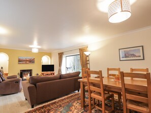 Ein Wohnzimmer mit einer Couch, einem Fernseher, einem Kamin und einem Essbereich mit Tisch und Stühlen.