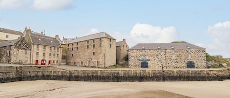 Une ville côtière avec des bâtiments en pierre, une plage de sable et un petit plan d’eau.