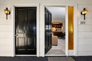 A black door with a brass doorknob, a white door with a brass doorknob, and a number '305' on the wall.