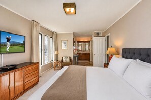 A hotel room with a large bed, a television, a desk, and a bathroom visible through an open door.