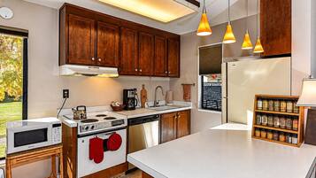 A modern kitchen with wooden cabinets, stainless steel appliances, and pendant lighting.