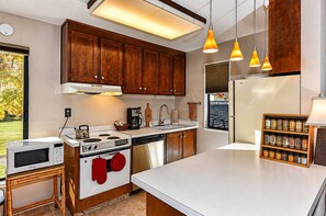 A modern kitchen with wooden cabinets, stainless steel appliances, and pendant lighting.