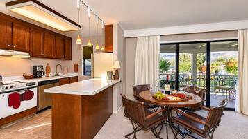 A modern kitchen with a central island, stainless steel appliances, and a dining area with a view of the outdoors.