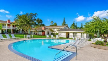 A swimming pool with lounge chairs and a small building in the background.