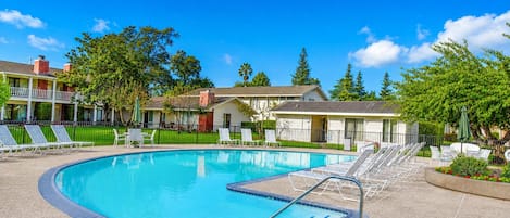 A swimming pool with lounge chairs and a small building in the background.