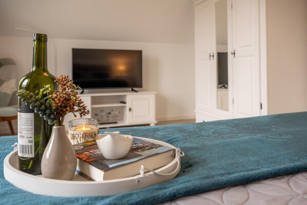 Un plateau bien rangé, sur lequel on a posé un livre, une bougie et un vase, sur un lit recouvert d’une couverture turquoise.