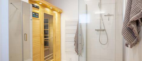 Un baño moderno con cabina de ducha de vidrio, un mueble de madera y un perchero para toallas.