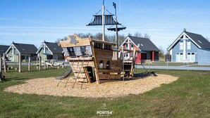 A playground with a pirate ship play structure, surrounded by houses. - Ferienhaus Marschengrün Büsum (Büsum)