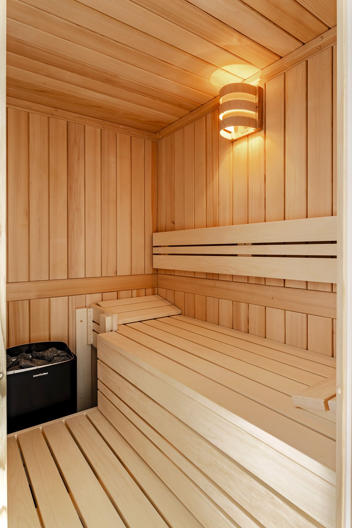 A sauna with wooden benches and a wall-mounted light fixture.