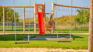Ein Spielplatz mit Rutsche, Schaukeln und einer Kletterkonstruktion.