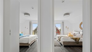 Une chambre moderne avec deux lits, une grande fenêtre et une vue sur une maison.