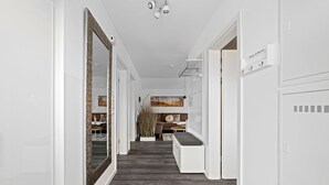 Un couloir moderne avec un grand miroir, un banc et un porte-manteau.