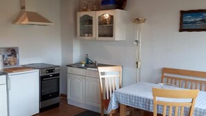 Una cucina compatta con mobili bianchi, un piano cottura e un lavello. C'è un'area pranzo con tavolo e sedie.