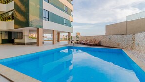 A modern building with a rooftop pool area, including lounge chairs and a clear blue pool. - RV09 Apto Vista Mar - Rio Vermelho (Salvador)