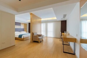 A hotel room with a bed, a desk, a chair, and a large window.