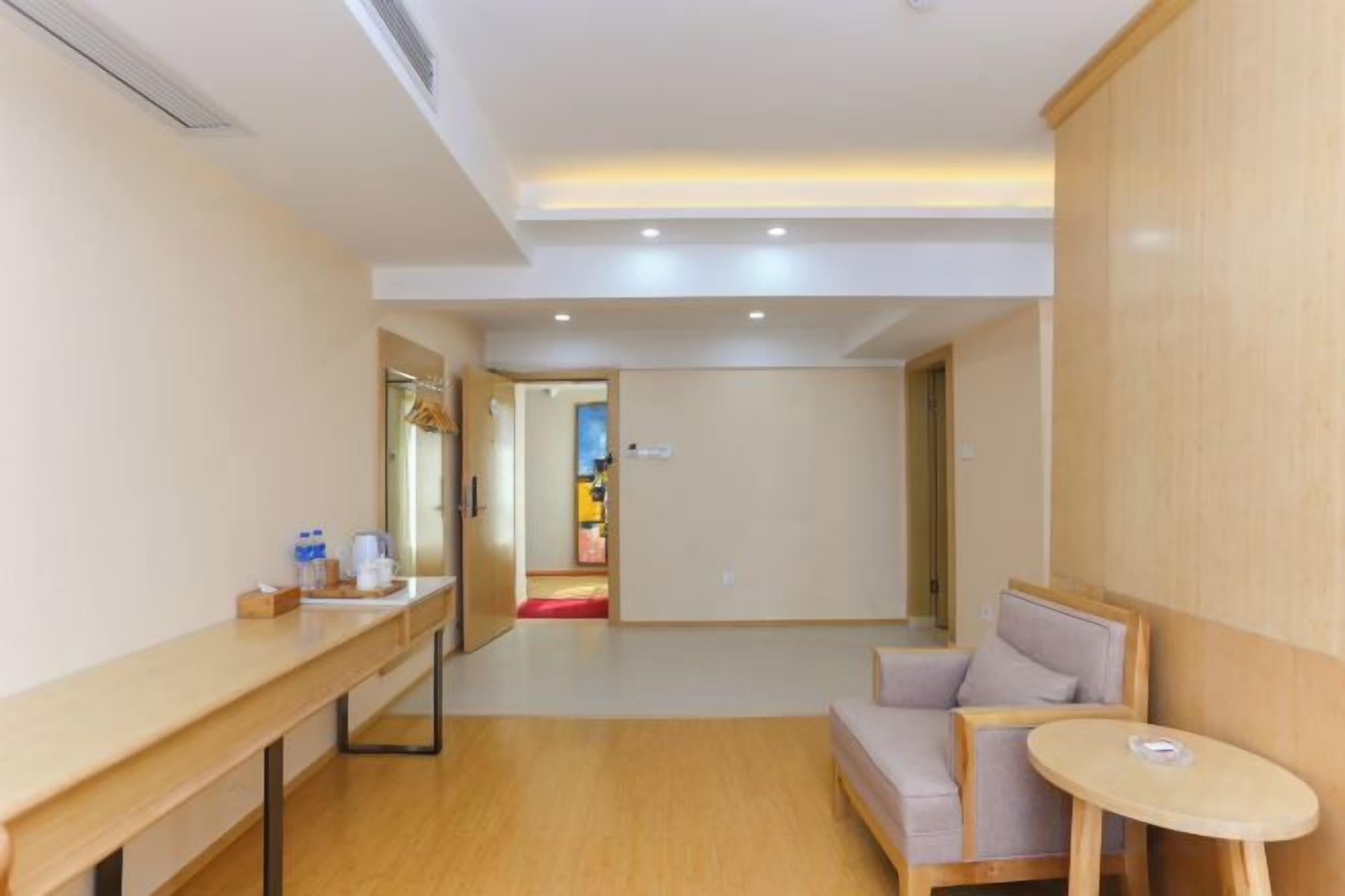 A hotel room with a wooden floor, a sofa, a small table, and a desk with a mirror.