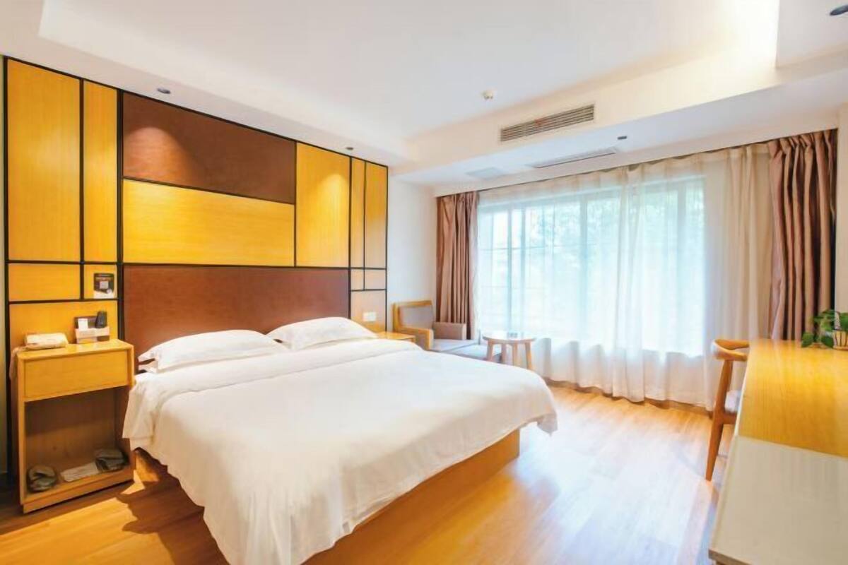 A hotel room with a large bed, a desk, and a window with curtains.