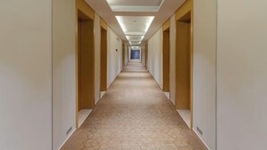 A long, narrow hotel corridor with doors on both sides, a patterned carpet, and recessed lighting. - Home Inn UP Huayi Collection (Lu'an Railway Station Branch) (Lu'an)