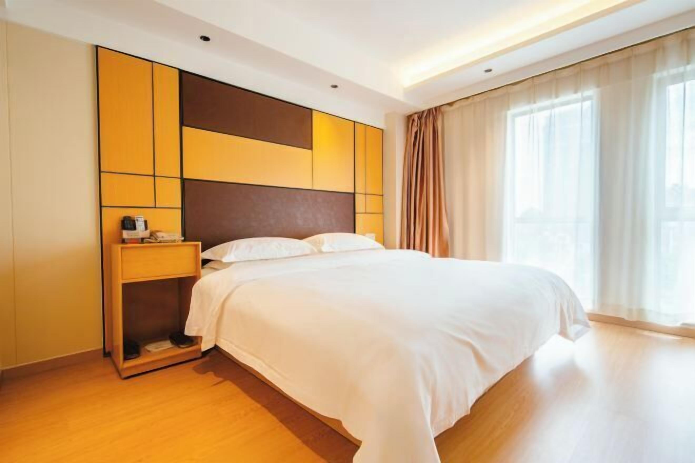 Una habitación de hotel moderna con una cama grande, una mesita de noche y un armario.