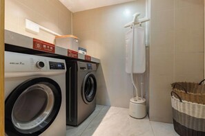 A laundry area with two washing machines, a drying machine, and a basket. - Home Inn UP Huayi Collection (Lu'an Railway Station Branch) (Lu'an)