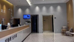 A hotel reception area with a modern design, featuring a reception desk, a television, and a seating area with chairs and a small table. - Home Inn UP Huayi Collection (Lu'an Railway Station Branch) (Lu'an)