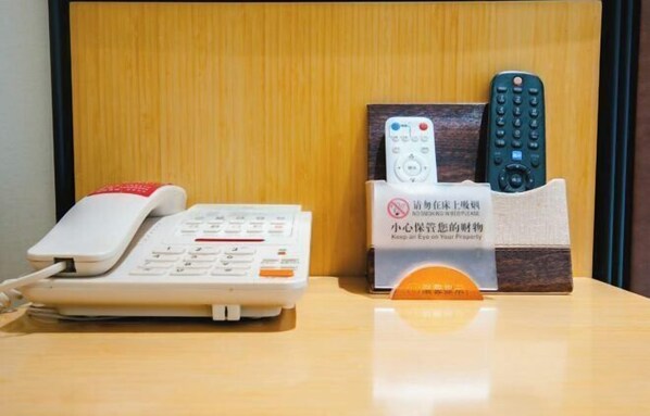 Une chambre d’hôtel équipée d’un téléphone, d’une télécommande et d’une pancarte avec du texte en chinois.