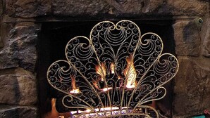 Une cheminée ornée d’un manteau en métal décoratif et de bougies allumées.
