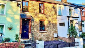 A stone house with a dark blue door, a small window, and a chimney. - A Superb Size Cottage By The Canal (Torfaen)