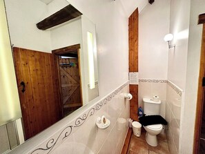 A bathroom with a wooden door, a white toilet, and a mirror. - 4 beautiful stone barns SlEEPS 17 People (Monmouthshire)