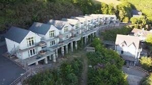 A large, multi-story building with a symmetrical facade, multiple balconies, and a central courtyard. - Sea Views, Hot tub, Balcony, 4 star Visit Wales (Pendine Camartheshire)