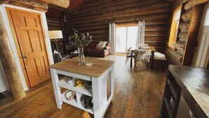 A cozy log cabin interior with a wooden dining table, a sofa, and a kitchen area. - Cozy, Modern Log Cabin Getaway ~ 20 Min to Winter Park (Tabernash)