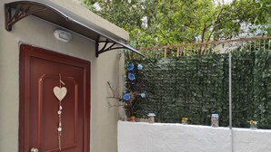 Una puerta roja con una decoración en forma de corazón, un toldo metálico y una pared cubierta de follaje verde.