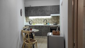 Una cocina compacta con una mesa de comedor y sillas, un refrigerador y un lavamanos.