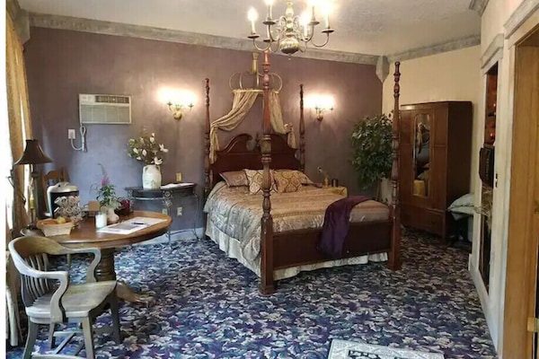 The guest house features a queen size bed, table, wardrobe, and mini-fridge.