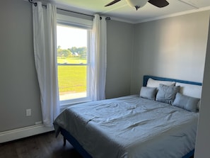 Una camera da letto con un letto, una finestra con tende e una ventola a soffitto.