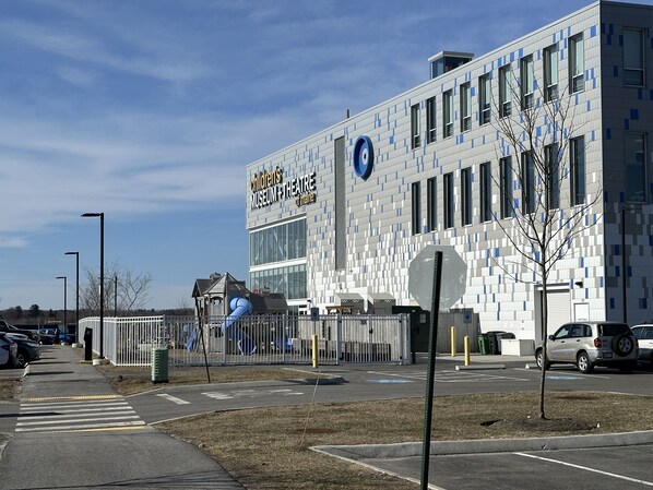 A children's museum and theatre with a modern architectural design, featuring a large glass facade and a distinctive blue circular logo.